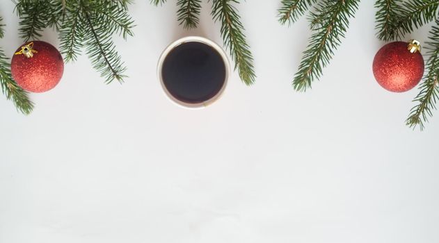 Christmas coffee.Top view, a cup of coffee and two red balls with christmas tree branches on white background,copyspace in the down