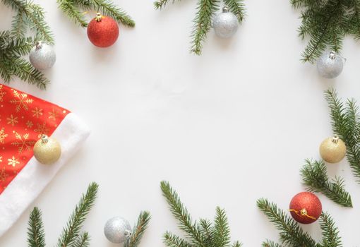 Christmas and new year composition.Top view, Santa hat with golden balls, two red balls and four silver balls and christmas tree branches on white background,copyspace.