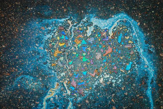 Oil stain on Asphalt road after rain. Abstract close-up background.