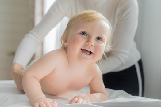 Mom gives her baby a shoulder and back massage. Close-up. A satisfied baby lies on the massage table.