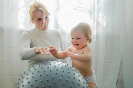 Mom is engaged in gymnastics with the baby on an inflatable ball. Fitball, gymnastics for a child.