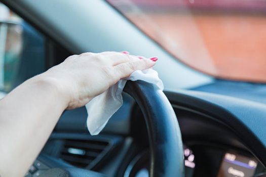 The girl wipes the steering wheel from dust with a napkin. Disinfects from germs. Close-up