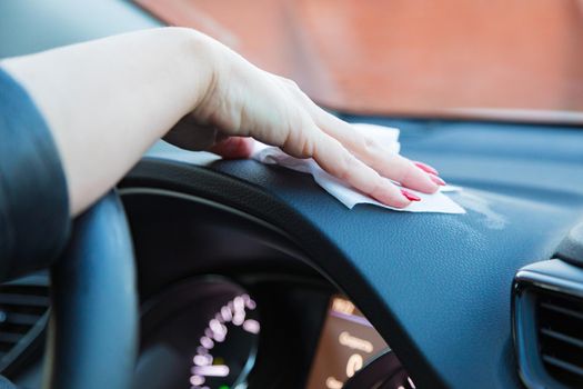 The girl wipes the control panel in the car from dust with a napkin. Disinfects from germs. Close-up