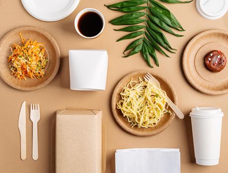 Eco friendly zero waste disposable tableware with pasta, salad and donut top view flat lay on brown background. Mock up design