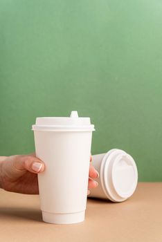 Eco friendly zero waste disposable tableware. White large takeaway paper coffee cups mock up on green and brown background