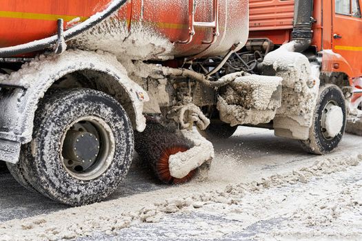 The machine with a mechanical brush clears the road from the snow. Close-up