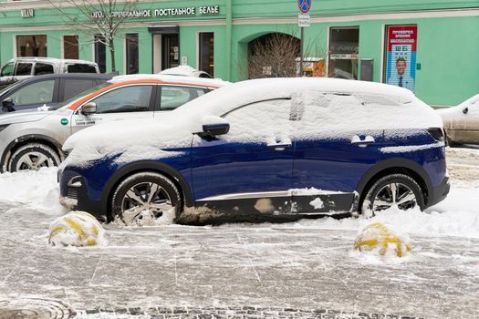 Saint Petersburg, Russia - February 21, 2021: A car covered with snow is parked on the street of the city