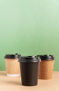 Eco friendly zero waste disposable tableware. Black takeaway paper coffee cups mock up on green and brown background