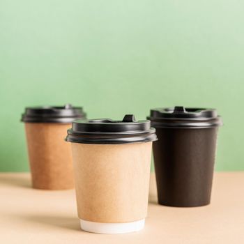 Eco friendly zero waste disposable tableware. Black takeaway paper coffee cups mock up on green and brown background