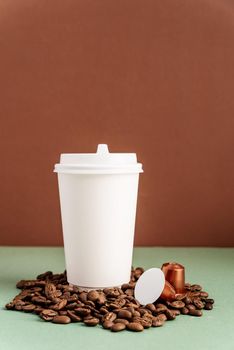 Zero waste and ecology concept. Eco-friendly disposable white paper cup with coffee beans and capsules, mock up design