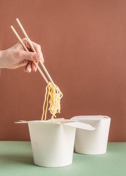 Zero waste and ecology concept..Opened WOK paper box for mock up design. Woman hand holding noodles with chopsticks