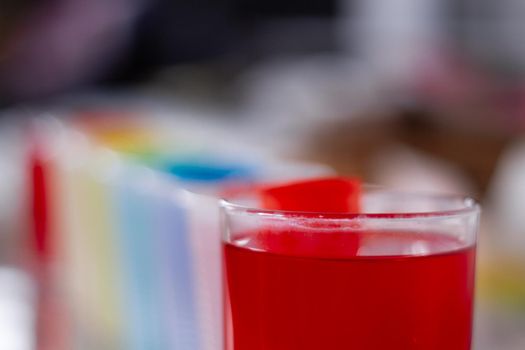 Detail of a group of glasses full of rainbow coloured liquids