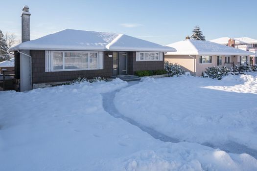 Pathway over front yard leading to average house cleaned from the snow