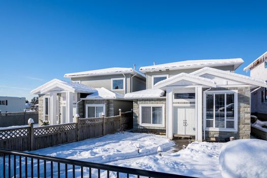 Residential duplex house with front yard in snow. North American family duplex house on bright winter day