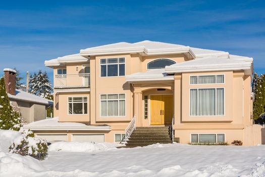 Luxury residential house with front yard in snow. North American family house on winter sunny day