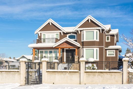 Luxury residential house with front yard in snow. North American family house on winter sunny day