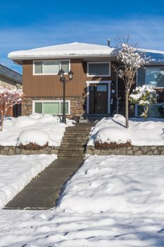 Pathway over front yard leading to average house cleaned from the snow