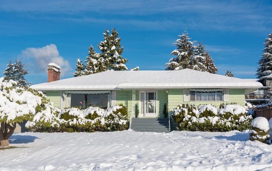 Family residential house with front yard in snow. North American house on winter sunny day