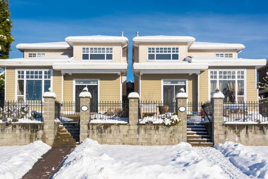 Residential duplex house with front yard in snow. North American family duplex house on winter sunny day