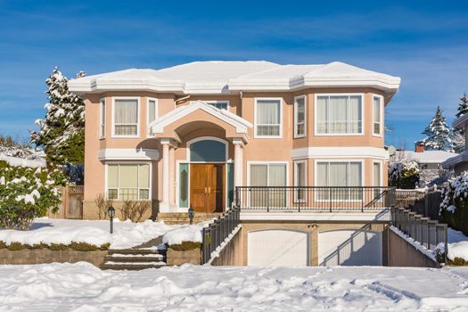 Luxury residential house with front yard in snow. North American family house on winter sunny day