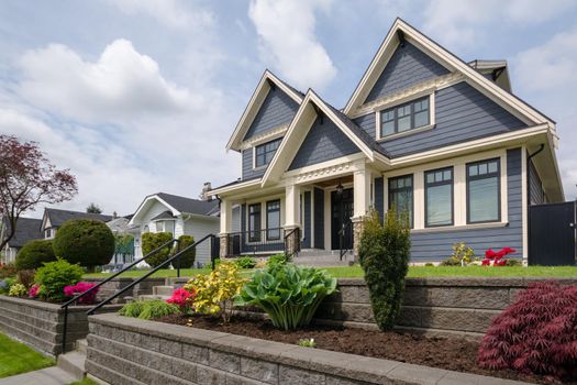 Luxury residential house with front yard over land terraces. Big family house with nice landscaping in front