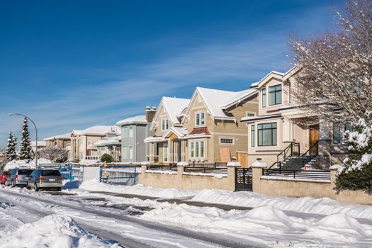 Street of brand new luxury houses with cars parked on the road on sunny winter day in British Columbia