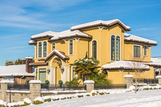 Luxurious residential house with front yard in snow. North American family house on winter sunny day