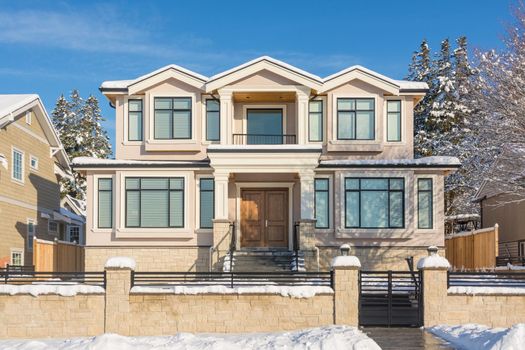Luxury residential house with front yard in snow. North American family house on winter sunny day
