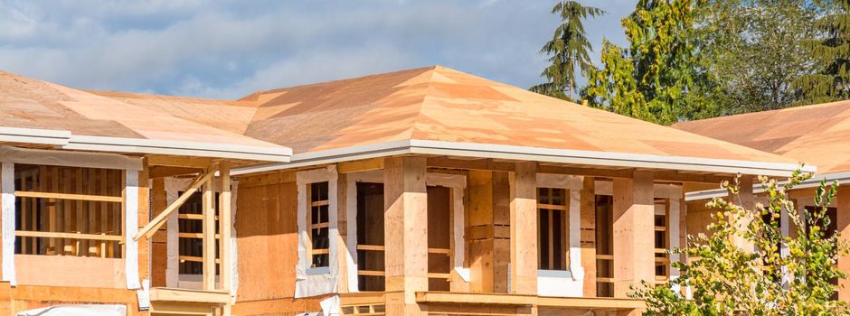 New roof of apartment building under construction on blue sky background