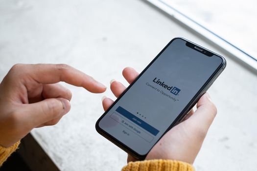 CHIANG MAI, THAILAND APR 27 2021 : A women holds Apple iPhone with LinkedIn application on the screen.LinkedIn is a photo-sharing app for smartphones