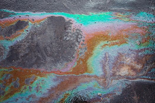 Color gasoline fuel spot on black asphalt, industrial concept. Beautiful abstract colorful background
