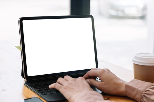 Close up hand of woman typing on smart tablet with blank white screen on table.