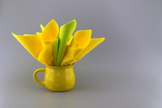 Yellow napkins placed in the yellow cup on gray background with free copy space