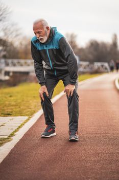 Active senior man is having pain in knees while jogging.