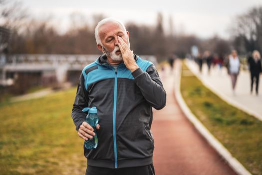 Active senior man is tired after exercising. Healthy retirement lifestyle.