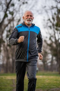 Happy senior man is jogging in park.