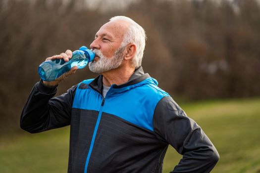 Active senior man is drinking water after exercising. Healthy lifestyle.