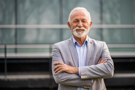 Outdoor portrait of senior businessman in front of company building.