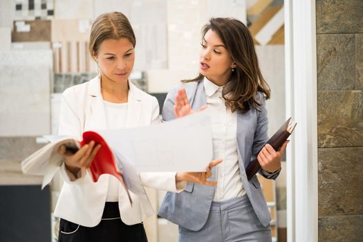 Businesswoman owning small business store. She is talking with a customer who is choosing the goods.