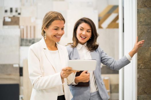 Businesswoman owning small business store. She is talking with a customer who is choosing the goods.