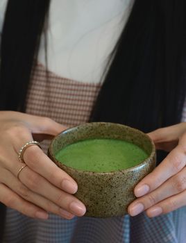 closeup hot matcha in female hand