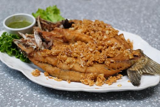stir fried seabass fish on white dish