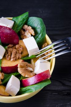 Spinach salad with nuts and apples served on table