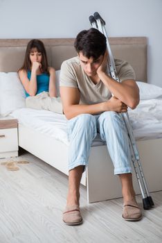 Young wife supporting husband on crutch after injury