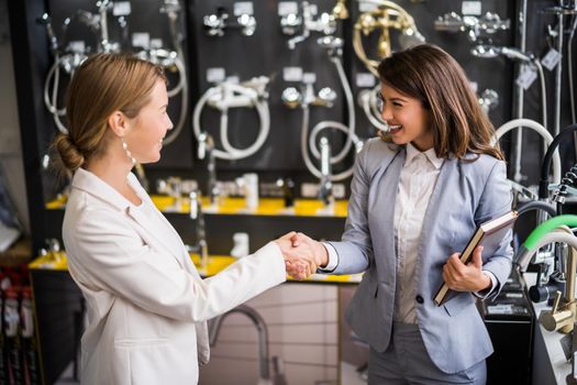 Businesswoman owning small business tiles store. She is handshaking with a satisfied customer.