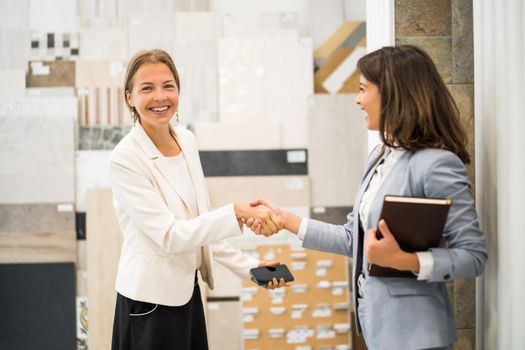 Businesswoman owning small business tiles store. She is handshaking with a satisfied customer.
