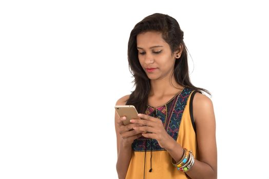 Portrait of a happy young girl using mobile phone isolated over white background