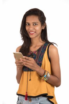 Portrait of a happy young girl using mobile phone isolated over white background