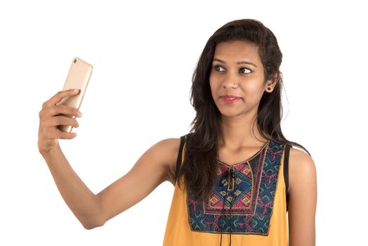 Portrait of a happy young girl using mobile phone isolated over white background