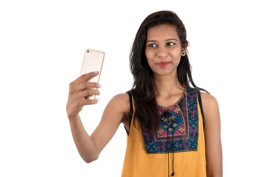 Portrait of a happy young girl using mobile phone isolated over white background